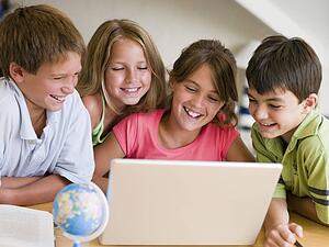 Group Of Young Children Doing Their Homework On A Laptop