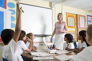 Student volunteering in class with teacher at board