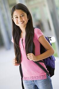 Student standing outside school smiling (selective focus)