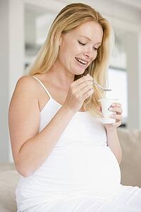 Pregnant woman with yogurt smiling