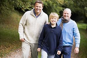 Two men and young boy walking on path outdoors smiling (selective focus)