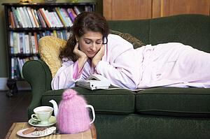 Young woman lying on sofa at home watching telephone