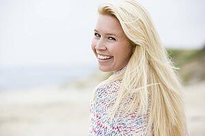 Woman standing at beach smiling