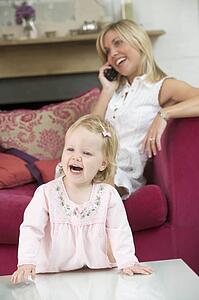 Mother using telephone in living room with baby smiling