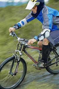 Man outdoors on trails riding bicycle (selective focus)