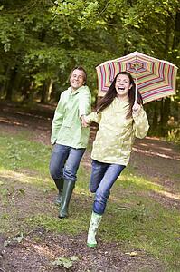 Couple outdoors running with umbrella smiling