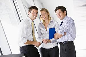 Three businesspeople standing in corridor smiling