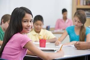 Students in class taking notes with teacher in background (selective focus)
