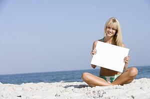 Woman holding a blank card on a beach