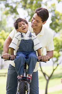 Man and young boy on a bike outdoors smiling