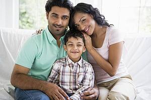Family in living room sitting on sofa smiling (high key)