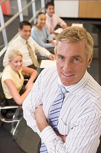 Businessman with four businesspeople at boardroom table in background