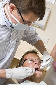 Dentist and assistant in exam room with man in chair