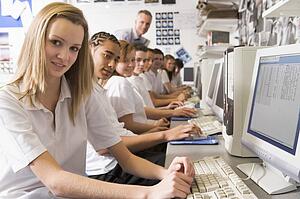 Students working on computer workstations with teacher