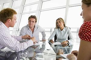 Four businesspeople in a boardroom with paperwork