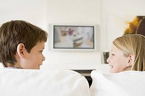 Young boy and young girl in living room with flat screen television