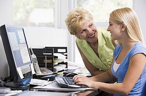 Woman and girl in home office with computer smiling