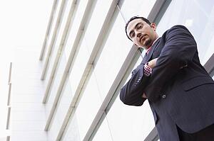 Businessman standing outdoors by building (high key/selective focus)