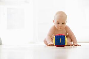 Baby sitting indoors with block