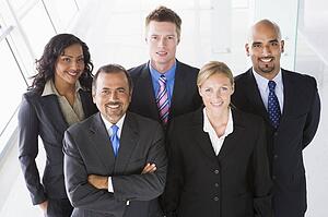 Group of co-workers standing in office space smiling (high key)