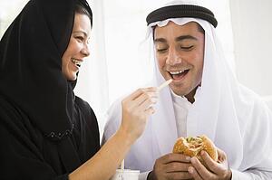 Couple eating fast food in living room and smiling (high key/selective focus)