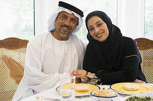Couple sitting at dinner table smiling (high key)