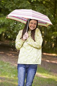 Woman outdoors in rain with umbrella smiling