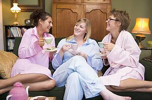 Three woman in night clothes sitting at home drinking tea