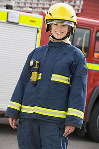 Firewoman standing by fire engine wearing helmet