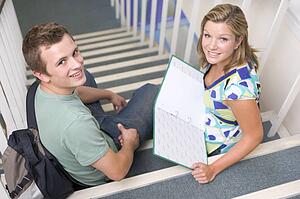 Two students sitting on staircase with notebooks (selective focus)