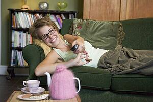 Young woman lying on sofa at home watching television