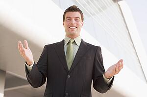 Businessman standing outdoors by building with hands out