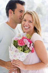 Husband and wife holding flowers and smiling