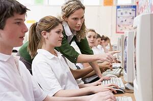 Students working on computer workstations with teacher