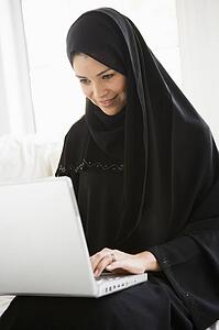 Woman in living room on laptop smiling (high key/selective focus)