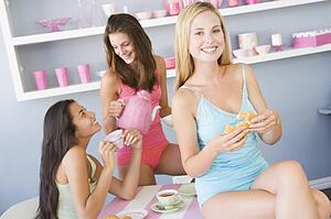 Three young woman sitting at a table having tea and a snack