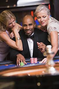 Three people in casino playing roulette smiling (selective focus)