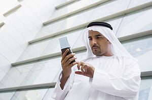 Businessman outdoors by building using PDA