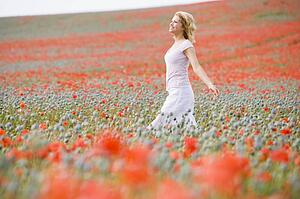 Woman walking in poppy field smiling
