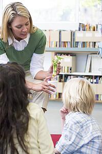 Teacher in class showing students bamboo plant (selective focus)
