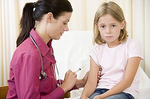 Doctor giving needle to young girl in exam room