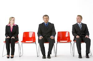Three Business People Sitting On Red Plastic Seats 