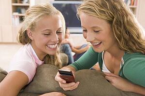 Teenagers Hanging Out In Front Of Television Using Mobile Phones 