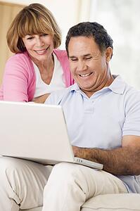 Couple in living room with laptop smiling