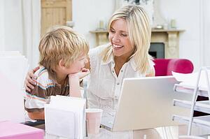 Woman and young boy in home office with laptop smiling