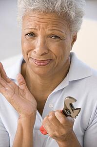 Woman holding wrench looking unsure