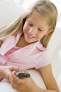 Young Girl Sitting On A Sofa Texting On A Cellphone