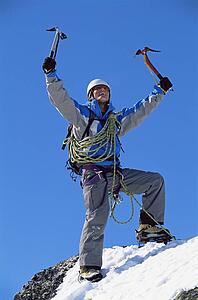 Mountain climber standing on snowy mountain victorious and smiling