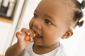 Young girl eating carrot indoors