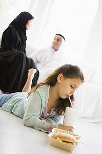 Young girl with fast food in living room with parents in background (high key/selective focus)